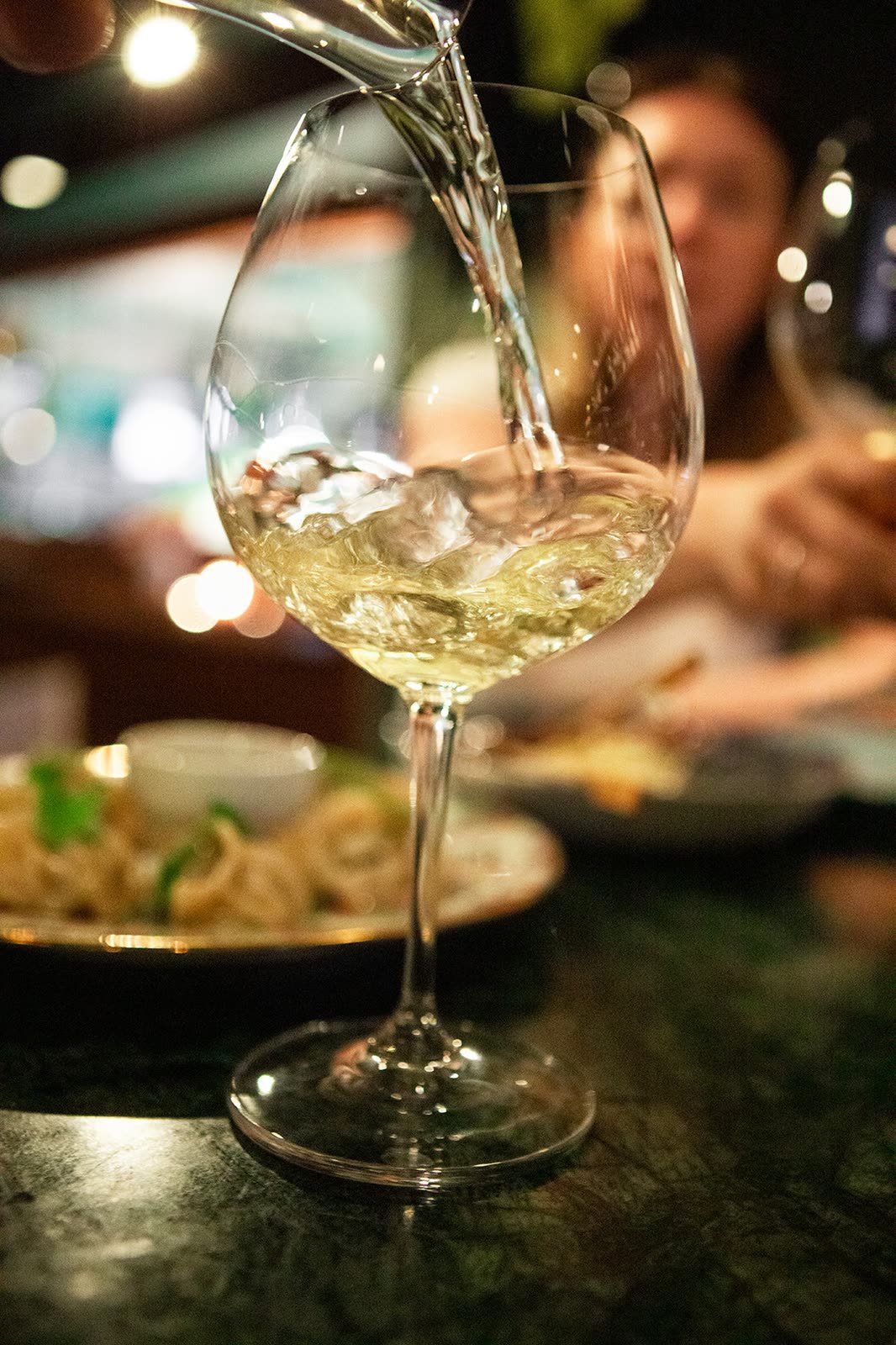 Hvitvin skjenkes i et glass i baren