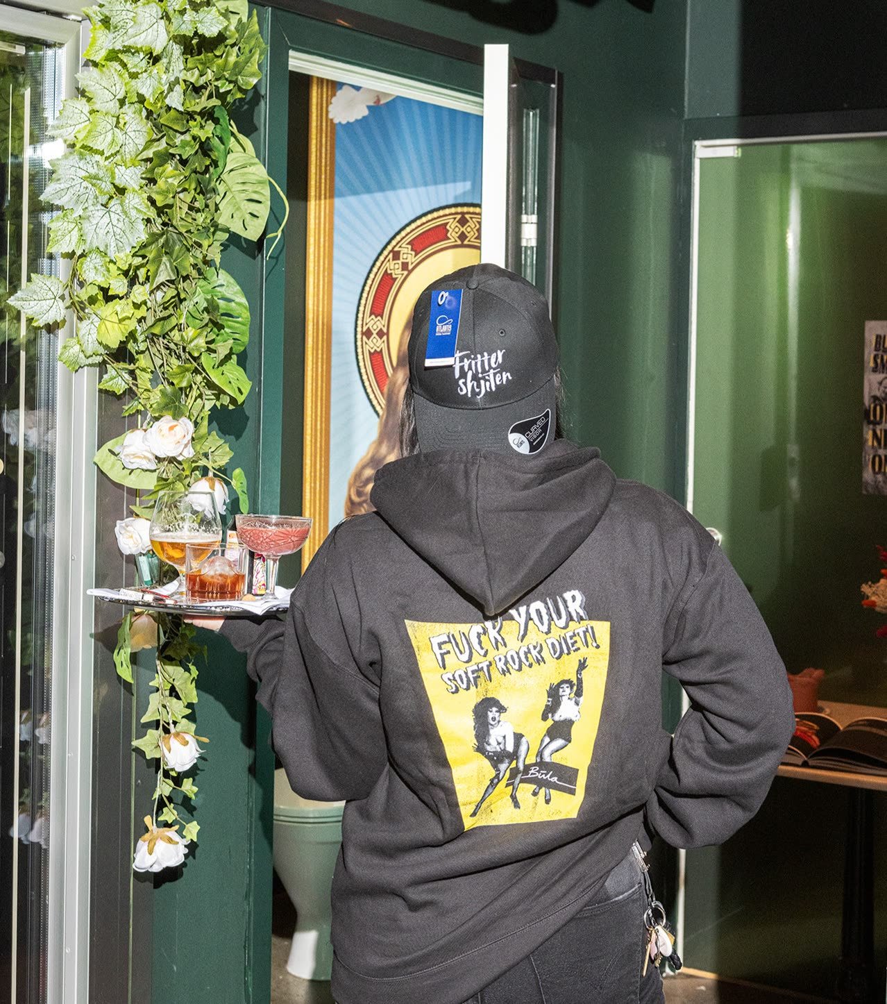 En person i Bula-hoodie og caps står i døra til restauranten